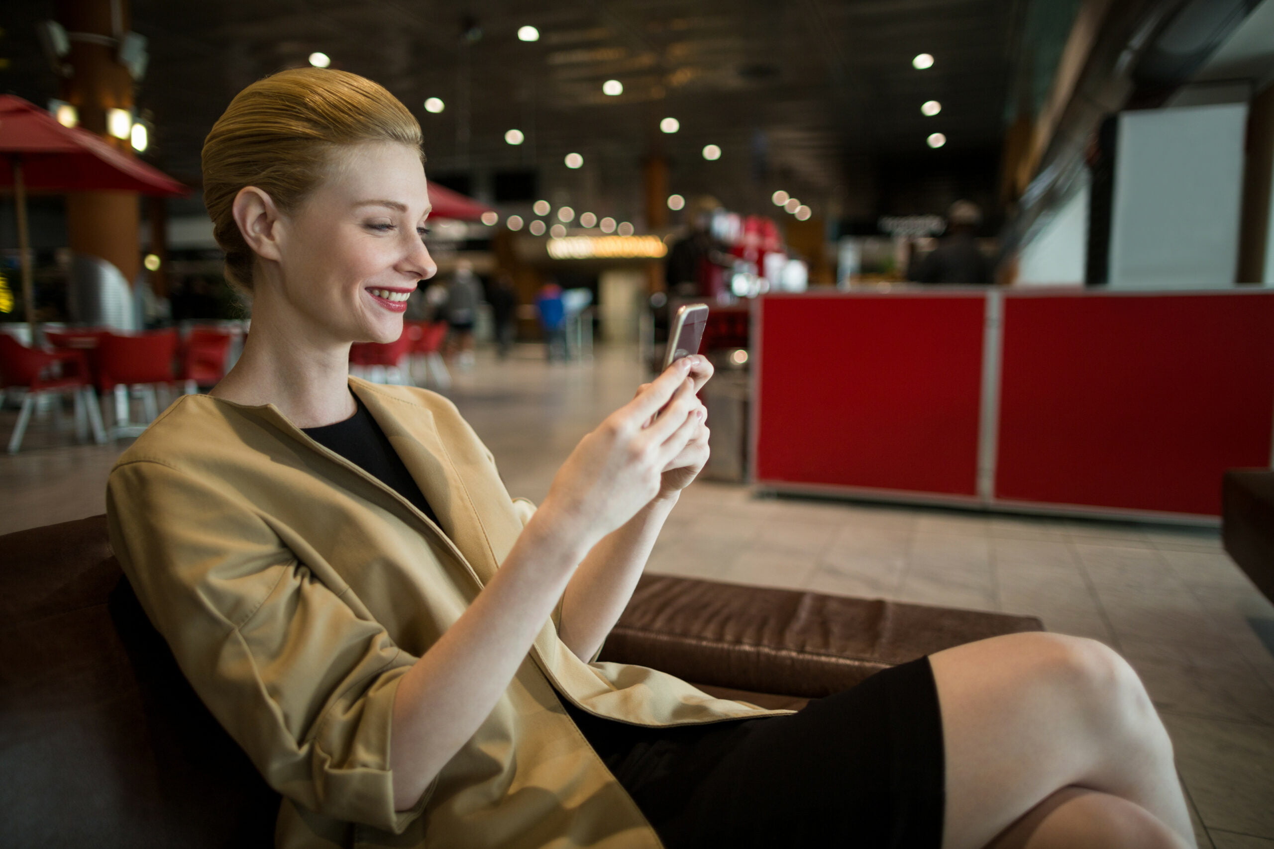 Mujer en sala de espera viendo en su celular las Mejores apps gratuitas de viaje