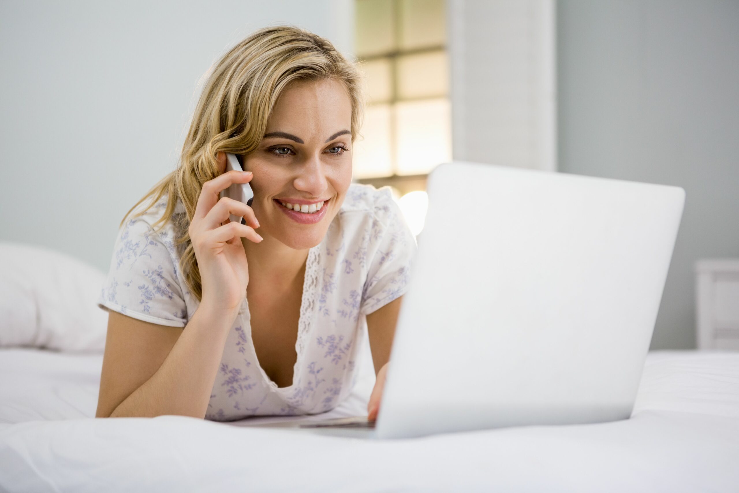 Mujer acostada en cama con su computadora siguiendo los consejos de como conseguir la mejor oferta de hotel