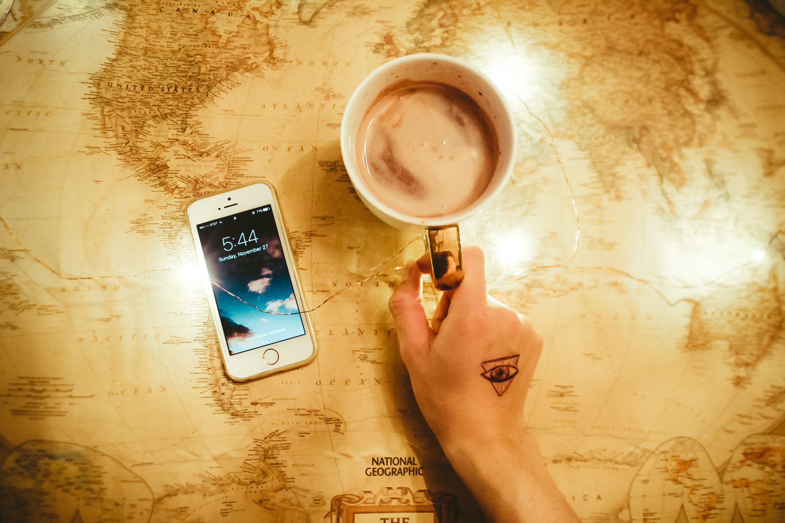 mejores apps de viaje en iPhone sobre un mapa y un mug de chocolate