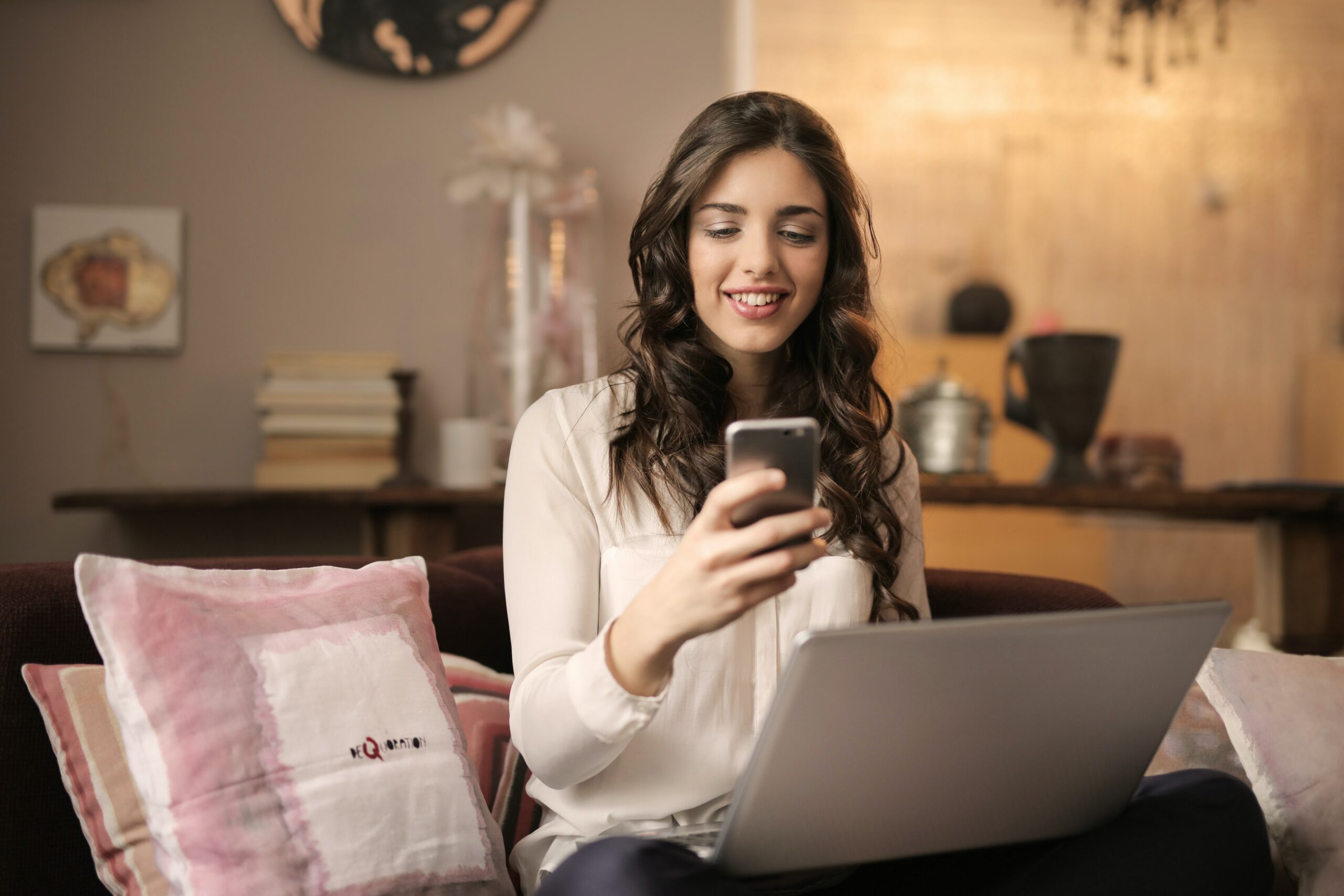 Mujer con su celular y computadora utilizando la mejor app para reservar un hotel